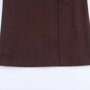 Close-up of dark brown textured wool fabric showing premium stitching on the coat hem