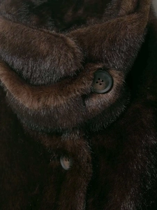 Detail of dark brown faux fur texture with high-quality resin button on collar