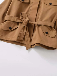 Detailed view of women's short trench coat waist with tie belt and contrast buttons