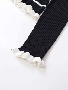Detailed macro view of black ribbed knit fabric with white ruffled edges and mesh hollow design