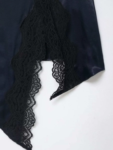 Detail of navy blue satin skirt hem with delicate black floral lace trim and side slit