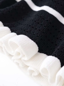 Close-up of contrast knit fabric with hollow honeycomb texture and white ruffle hem