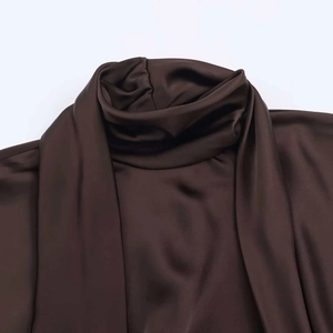 Detail of dark coffee satin dress featuring a high halter neckline and silky fabric texture