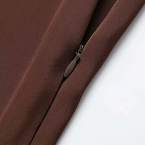 Detail of dark brown satin skirt featuring a seamless hidden zipper and lace stitching