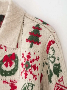 Makroansicht des cremefarbenen Weihnachtspullovers mit grünen Bäumen und roten Schneeflocken