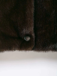 Close-up of deep brown faux fur texture and a round black button on a winter jacket