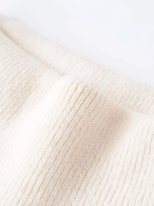 Macro view of white ribbed knit fabric showing soft texture and shoulder cut-out detail