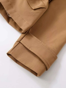 Detail shot of khaki trench coat cuff strap and pocket flap with premium stitching