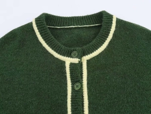 Detail of dark green knit cardigan with contrast cream trim and matching resin buttons