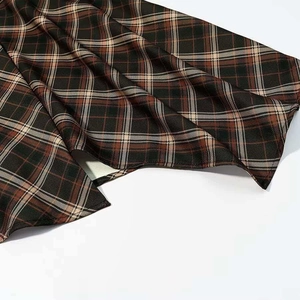 Détail de la jupe plissée à carreaux marron avec motif rétro et fente à l'ourlet
