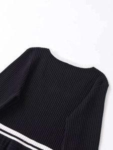 Detail of the white ribbed neckline and black textured knit fabric on a long sleeve top
