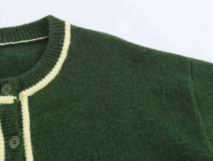 Close-up of dark green wool knit cardigan featuring cream contrast trim and buttons