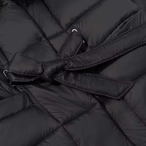 Close-up of black quilted puffer coat with waist belt bow and faux fur collar detail