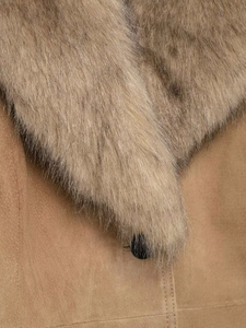 Détail du col en fausse fourrure amovible et texture suédine camel avec bouton noir