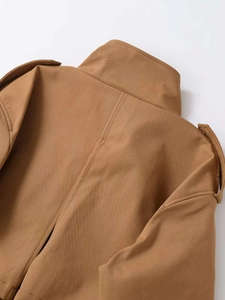 Close-up of khaki trench coat detail featuring shoulder epaulettes and twill fabric texture