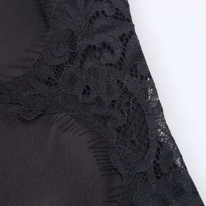 Gros plan sur satin noir avec dentelle florale délicate et détails de franges fins
