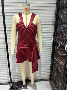 Detail of burgundy satin mini dress featuring V-neckline and asymmetrical knotted pleats