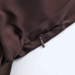 Close-up of the high-quality invisible zipper on a dark brown satin dress fabric