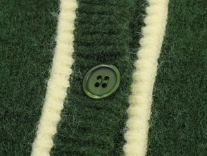 Macro shot of dark green knit cardigan featuring contrast white stripes and round button