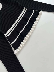 Detail of ribbed knit top with contrast white stripes and ruffled hem decoration