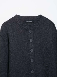 Close-up of dark grey knitted cardigan with round neck and detailed button closure texture
