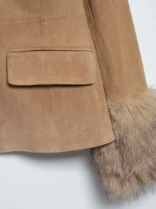 Détail macro de veste en daim camel montrant une poche plaquée et des poignets en fourrure