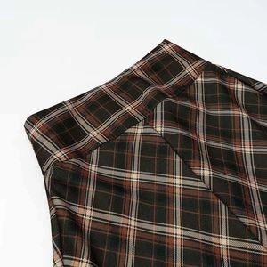 Gros plan sur la taille haute d'une jupe écossaise aux tons marron et beige