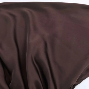 Macro shot of dark brown satin fabric showing smooth silk-like texture and soft drapes