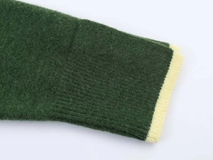 Close-up of dark green knitted sweater cuff with contrasting light yellow ribbed edge