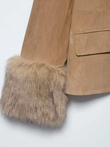 Gros plan sur la texture en daim et la bordure en fausse fourrure d'une veste courte camel