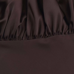 Macro detail of dark brown satin fabric featuring gathered textures on a summer mini dress