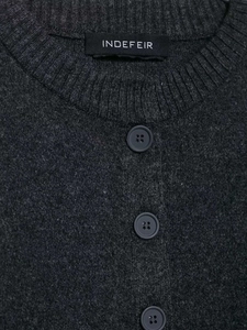 Close-up of the ribbed crew neck and button detail on a dark grey knitted sweater