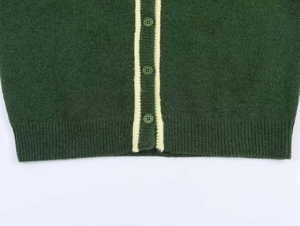Detail of dark green knit cardigan featuring contrast white stripes and buttons