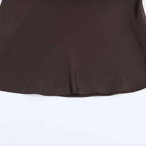 Detail of the smooth dark brown satin fabric hem with high-quality stitching on the dress