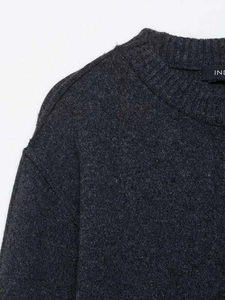Detail of the crew neck and shoulder seams on this dark grey fine-knit sweater