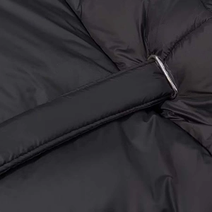 Detail of black quilted coat with a silver metal D-ring buckle and fabric belt texture