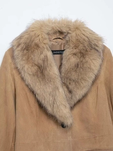 Détail d'une veste en daim camel avec col en fausse fourrure et étiquette Indefe