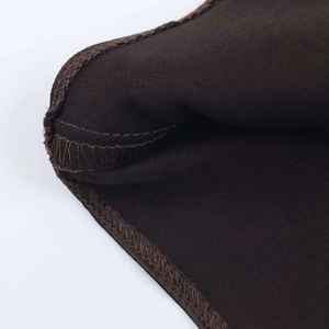 Detail shot of overlock stitching on dark brown satin texture short dress fabric