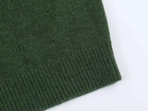 Detailed macro view of dark green knit fabric with soft texture and ribbed hem finishes