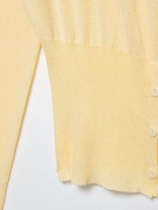 Close-up of pale yellow knit cardigan showing ribbing texture and matching round buttons
