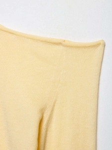 Detailed close-up of light yellow knit top with soft texture and rolled neckline finish