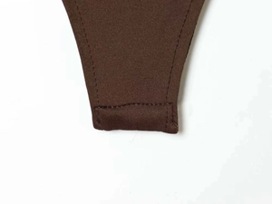 Detail van de drukknoopsluiting en stiksels aan de onderkant van de bruine romper