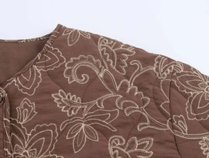 Detailed close-up of brown quilted jacket featuring white paisley embroidery and diamond patterns