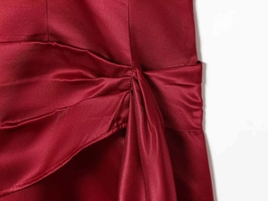 Detail of burgundy satin dress showing waist twist knot and draped silk fabric texture