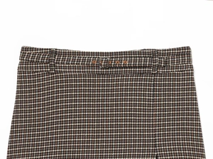 Détail de la taille d'une jupe en laine à carreaux avec ceinture assortie et boucle en métal
