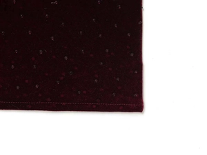 Macro shot of burgundy velvet fabric with sparkling sequins and stitched bottom hem details