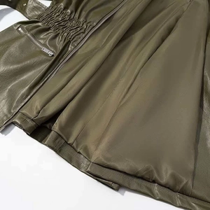 Close-up of olive green leather jacket with elastic waist and metal zipper detail