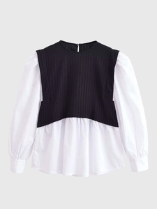 Close-up of black knit vest and white cotton puff sleeve layering on a two-piece top