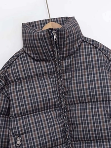 Detailed view of plaid quilted jacket with stand collar and metallic silver front zipper