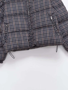 Detail of plaid quilted jacket featuring metal zipper pockets and adjustable hem drawstring